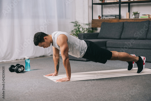bi-racial man doing push ups in sportswear on fitness mat