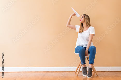 Young woman with a paper airplane in a chair
