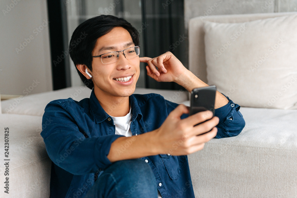 Happy asian man sitting at a couch at home Happy asian man sitting at a couch at home