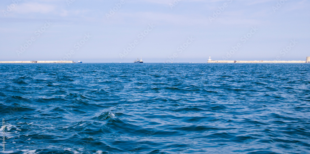Summer seascape with barriers of the Sevastopol Bay. Sea Gate of Sevastopol. Ships in the inner raid. Blurred wave motion. The bay forms the seaward approach to the city.