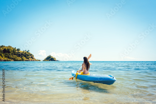 Frau paddelt in ihrem Kajak auf dem Meer im klaren Wasser