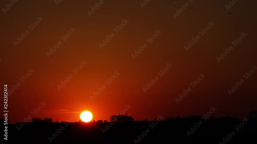 Wide shot of the luminous sun setting over a vivid orange sky touching the dark city rooftops in Istanbul Wide shot of the luminous sun setting over a vivid orange sky touching the dark city rooftops in Istanbul