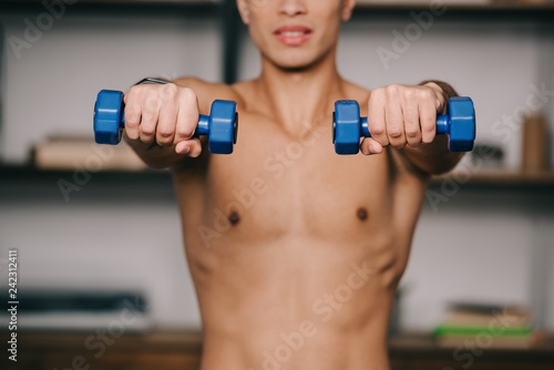 cropped view of mixed race man exercising with blue dumbbells