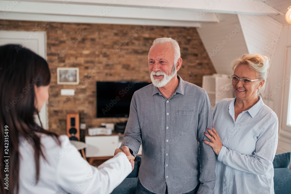 Fototapeta premium Senior couple welcoming female doctor during home visit.