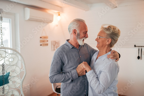 Affectionate senior couple dancing at home.