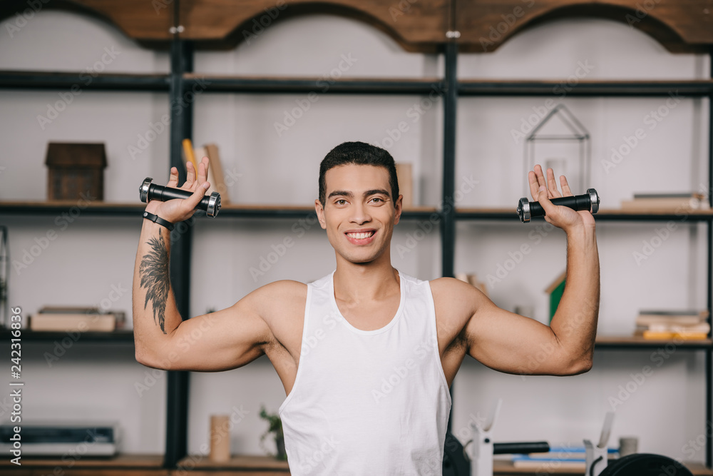 tattooed bi-racial man exercising with dumbbells tattooed bi-racial man exercising with dumbbells