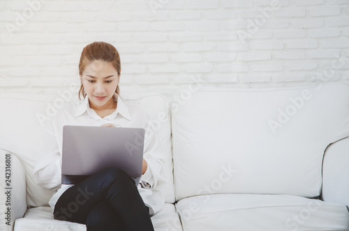 Beautiful woman's sofa is working on her laptop.Woman sitting in a white room..