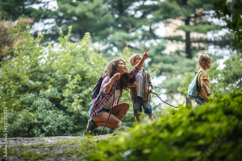 Mother and her little sons hiking trough forest .They learning about animal and plant life.