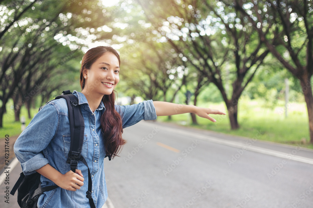 Asian women tourists and backpackers waiting car and Freedom traveler woman standing with raised arms at the roadside.