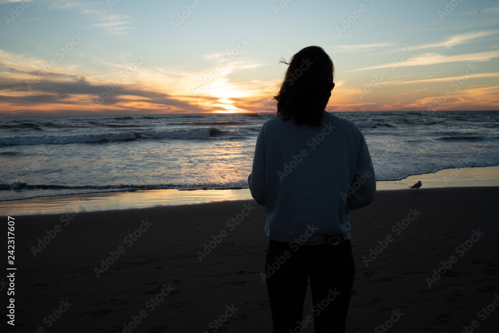 sad girl on the beach looking at the sunset