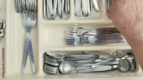 a man opens a drawer and takes some silverware