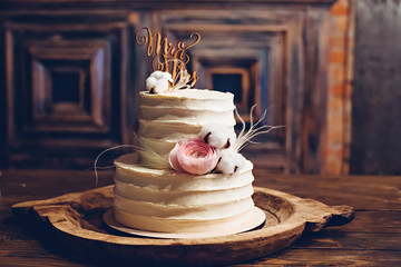 Rustic style wedding cake with cotton and floral decoration.