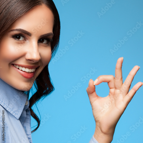 Showing okay gesture businesswoman, on blue photo