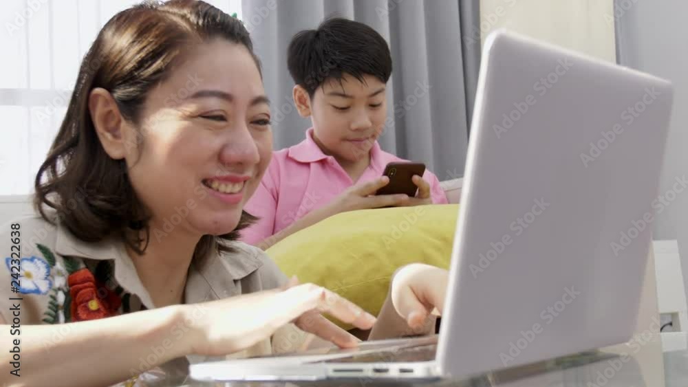 4K Family lifestyle is playing computer games. Asian Mother and son watching on laptop computer with smile face. 4K Family lifestyle is playing computer games. Asian Mother and son watching on laptop computer with smile face.