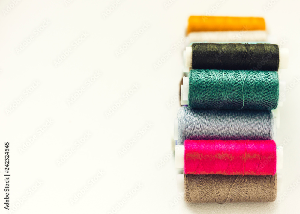 Colored sewing thread coils on white background with copy space for text. Colored sewing thread coils on white background with copy space for text.