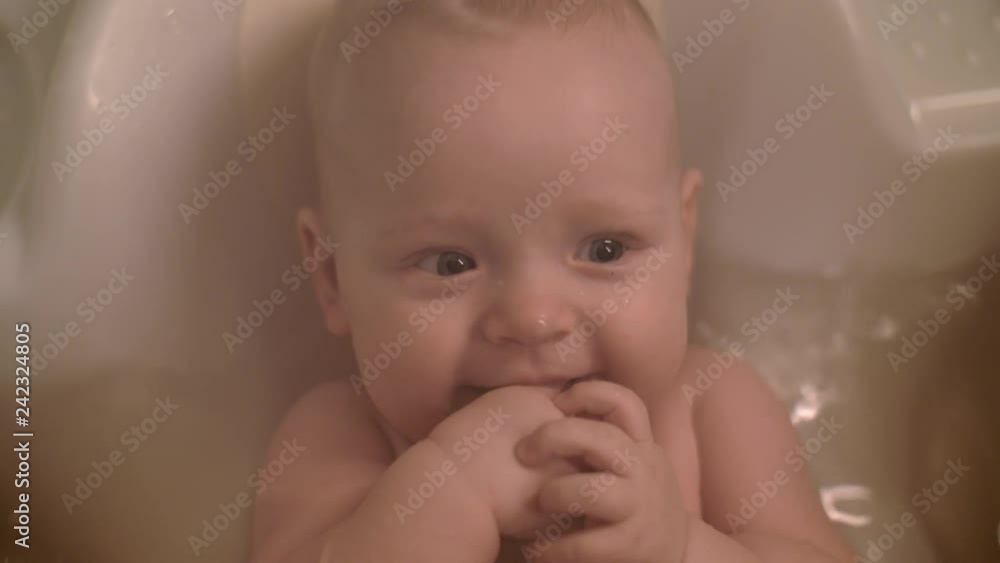 Slow motion close-up shot of cheerful baby girl bathing. Lovely blue-eyed child in water Slow motion close-up shot of cheerful baby girl bathing. Lovely blue-eyed child in water