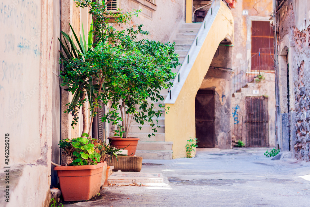 Fototapeta premium Bench and plants in tubs in the courtyard of the house in Catania, Sicily, Italy.