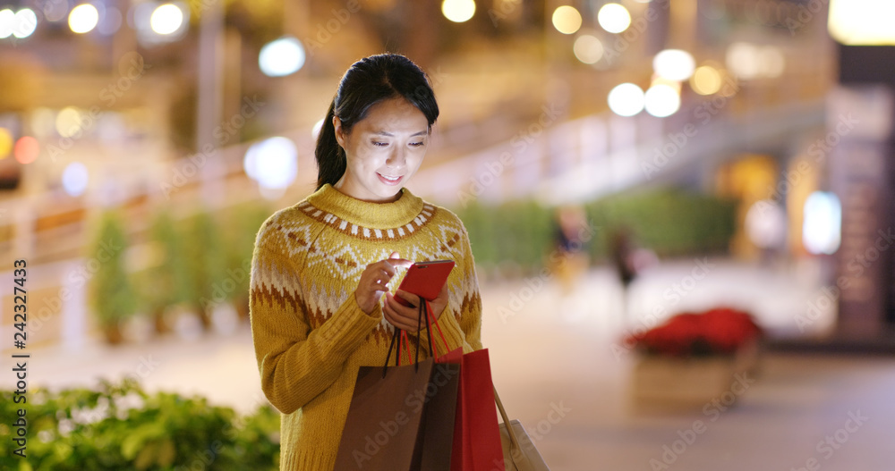 Woman hold shopping bag and use of mobile phone