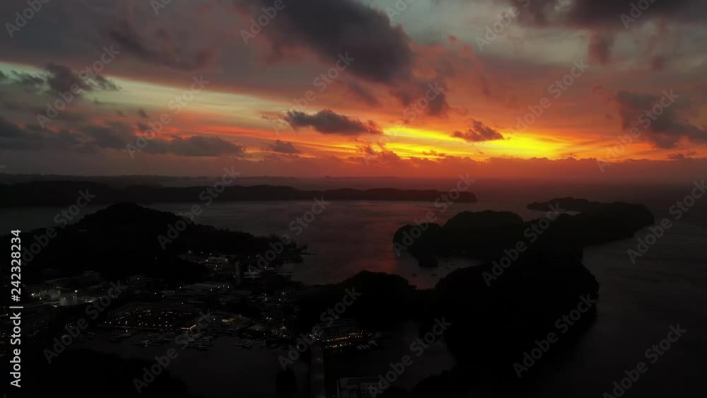 Aerial view of sunset on Koror island, stunningly colorful clouds, silhouettes of islands, orange sky reflection in waters of Pacific Ocean - landscape panorama of Palau at night, Micronesia Aerial view of sunset on Koror island, stunningly colorful clouds, silhouettes of islands, orange sky reflection in waters of Pacific Ocean - landscape panorama of Palau at night, Micronesia