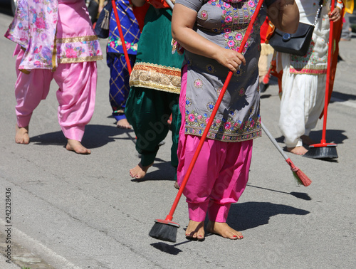 barefoot women of Sikh religious sweep the road with brooms