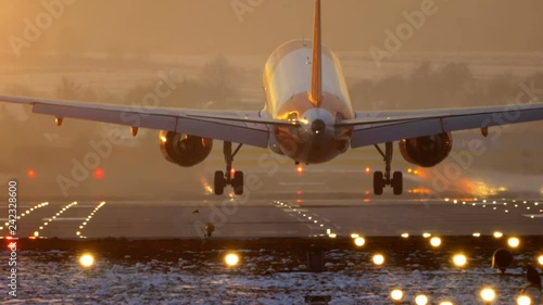 Commercial Jet Airplane Landing in airport runway at sunset in Winter. Slow Pan. photo