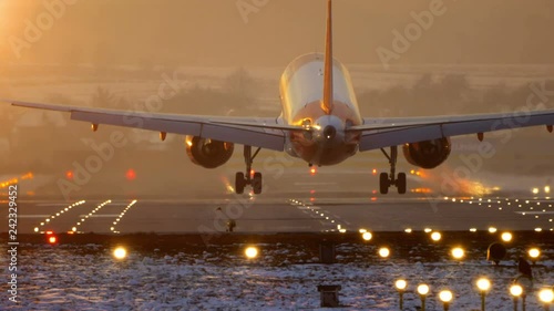 Commercial Jet Airplane Landing in airport runway at sunset in Winter.