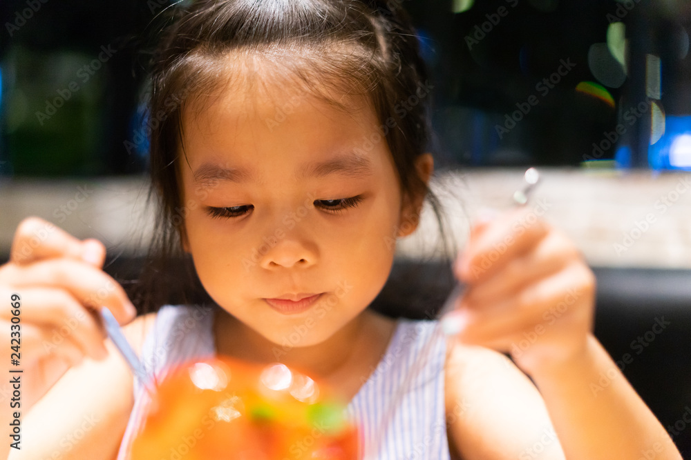 Happy asian child girl eating ice cream and she have spoon in her mouth in restaurant.Enjoying delicious face. Happy asian child girl eating ice cream and she have spoon in her mouth in restaurant.Enjoying delicious face.
