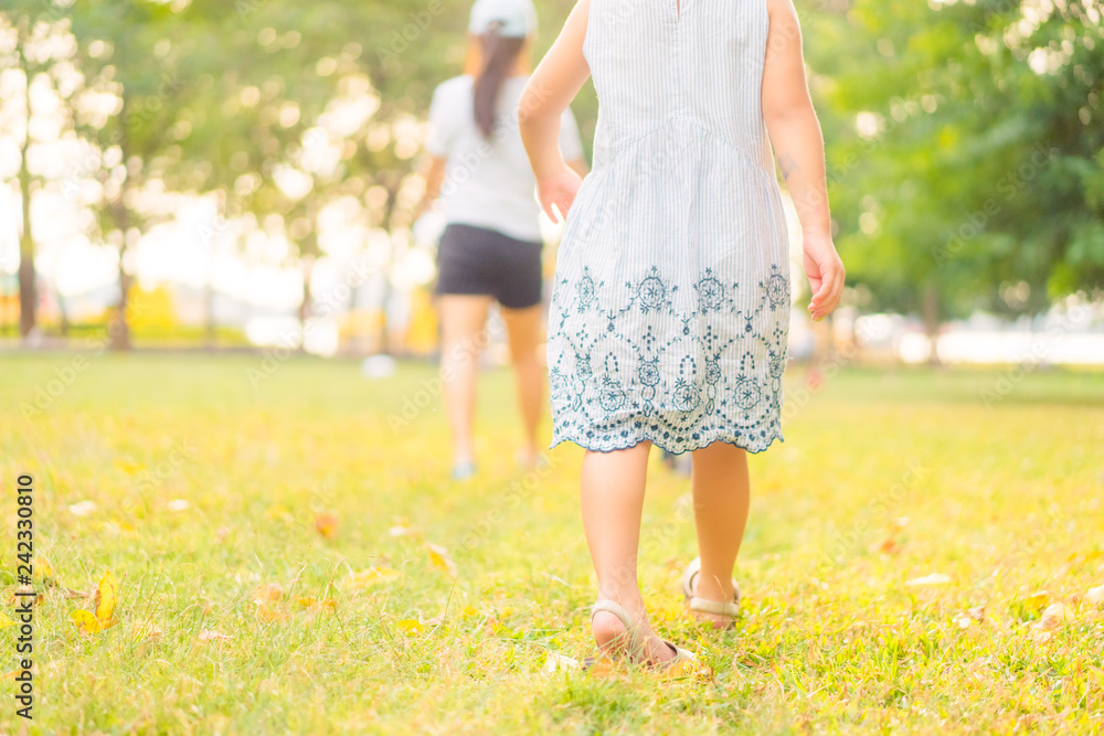 Back view of 5 years old cute little girl playing in sunny summer park.Happy kid girl walking and jumping in a forest.Kids play outdoors.Kindergarten in school yard on summer day. Back view of 5 years old cute little girl playing in sunny summer park.Happy kid girl walking and jumping in a forest.Kids play outdoors.Kindergarten in school yard on summer day.