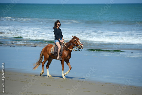 Woman riding on a horse along the ocean shore