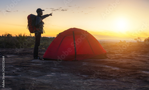 Senior backpacker standing beside tent on the hill in during sunrise is holiday of he