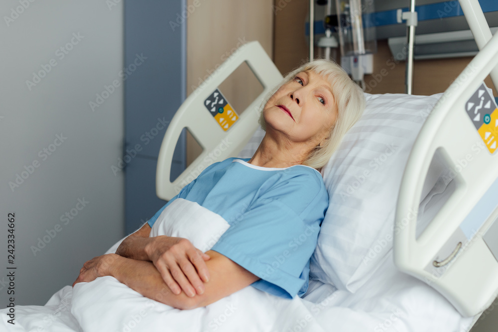senior woman with hands crossed lying in bed in hospital senior woman with hands crossed lying in bed in hospital