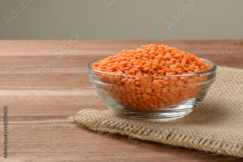 Lentejas naranjas crudas en un bol en la mesa de madera