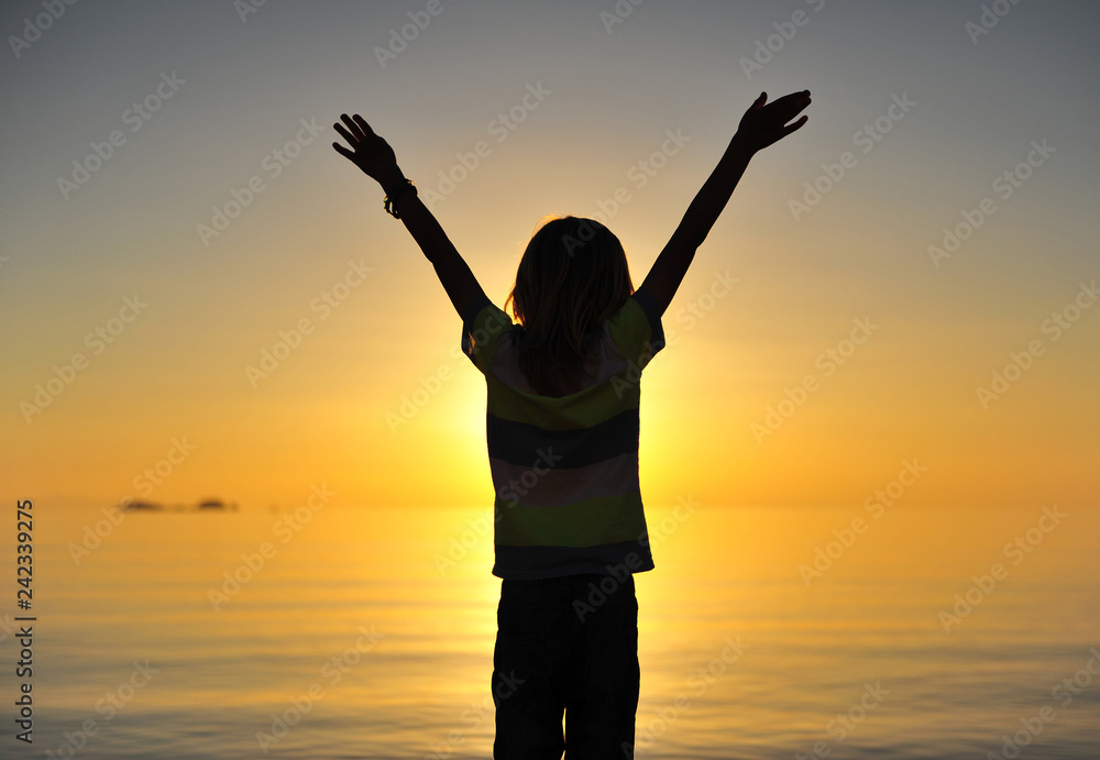 Little boy standing at sea on sunset