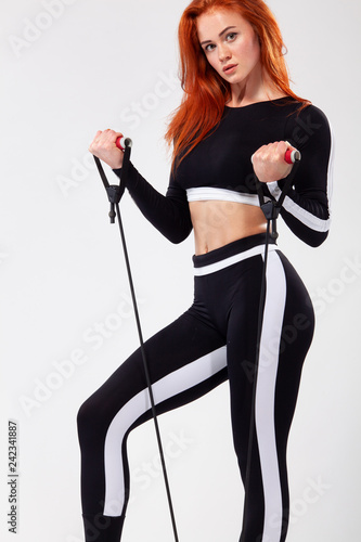 Sporty fit woman, athlete with expander makes fitness exercising on white background.