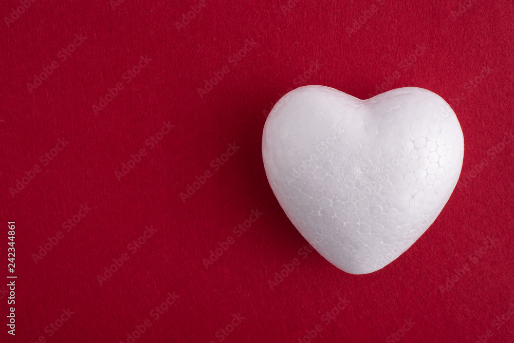 White foam heart on a red felt background White foam heart on a red felt background