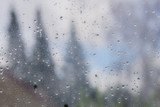 Drops of rain and condensation on the window, blurred trees in the background