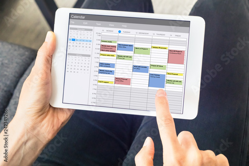 Calendar app on tablet computer with planning of the week with appointments, events, tasks, and meeting. Hands holding device, time management concept, organization of working hours planner, schedule photo