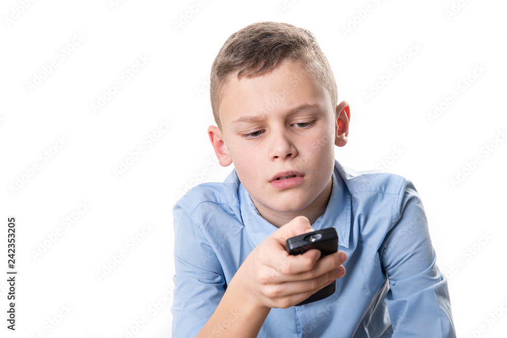 Boy with a blue shirt holds a remote control in his hand and tries to operate it