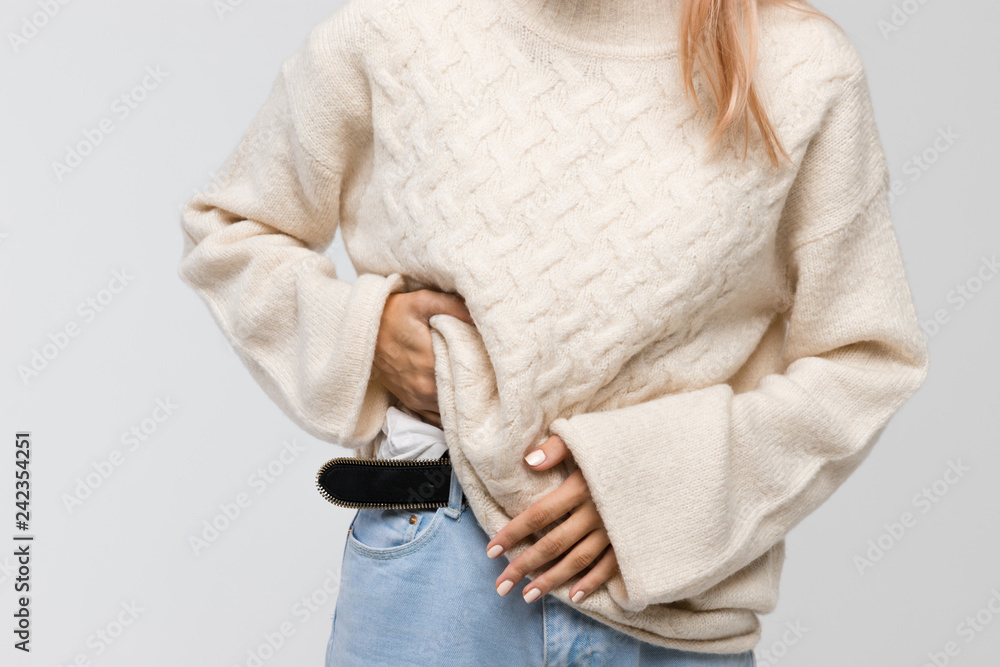 Φωτογραφία Cropped shot of young woman in white sweater suffering from stomach ache, having menstruation pain, feels bad, front view
