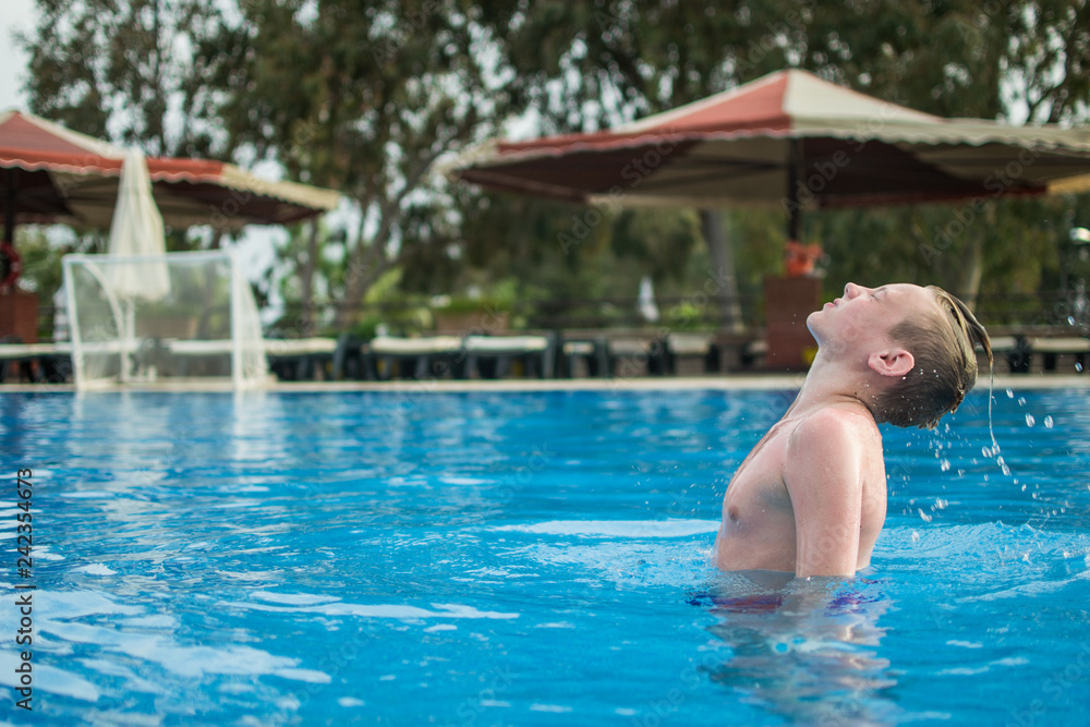 Happy teen boy in pool at aqua park