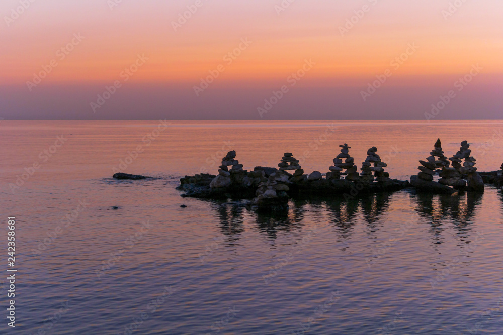 Relaxing pink sea sunset with stones.