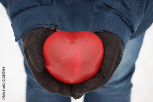 red balloon in the shape of a heart man holds in his hands. gift on a frosty day on February 14-Valentine's day. marriage proposal. romantic couple's love