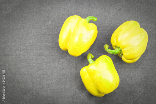 three yellow sweet pepper on dark textile background, top view