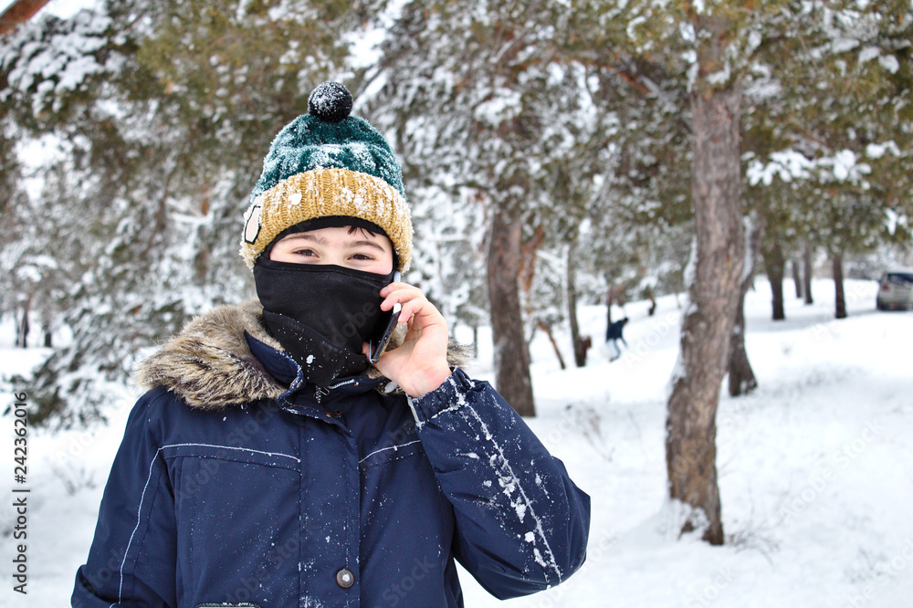 talking on the phone boy in a knitted hat with a bubo and balaclava on a winter walk talking on the phone boy in a knitted hat with a bubo and balaclava on a winter walk