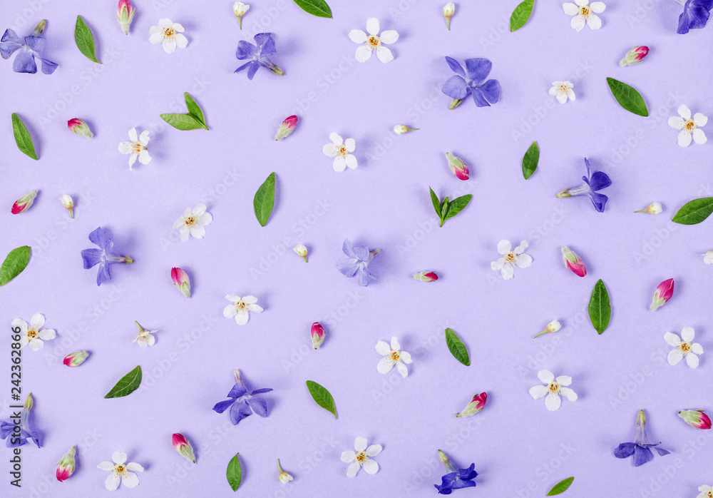 Floral pattern made of spring white and violet flowers, green leaves and pink buds on pastel lilac background. Flat lay. Top view. Floral pattern made of spring white and violet flowers, green leaves and pink buds on pastel lilac background. Flat lay. Top view.