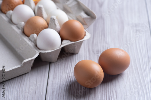 Raw eggs in egg box on wooden background.
