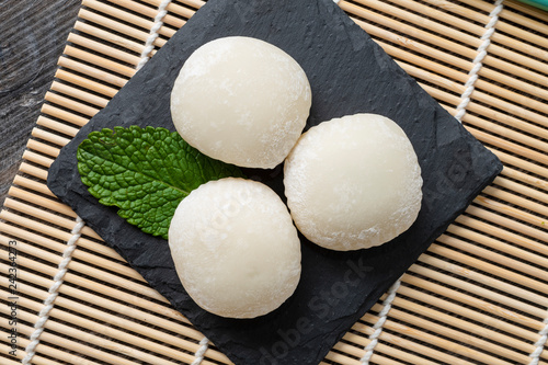 Japanese mochi with mint leaves on the wooden mat. Japan traditional rice cake. photo