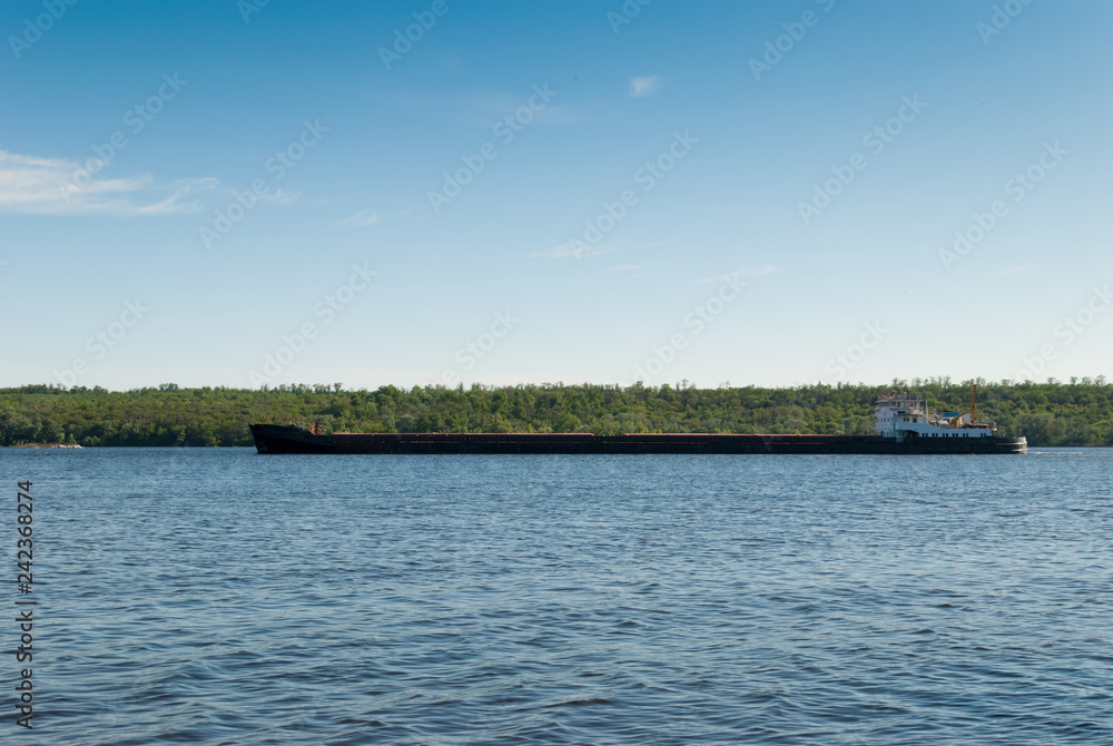 Barge sails along the island, river, sea, ocean, in the background of the forest