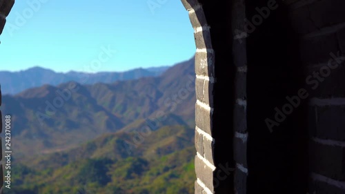 Steadicam shot of the Chinese Great wall that rises up the side of the mountain in a begining of fall. Camera moves through the passage in the watchtower and shows the view from the window on the wall photo