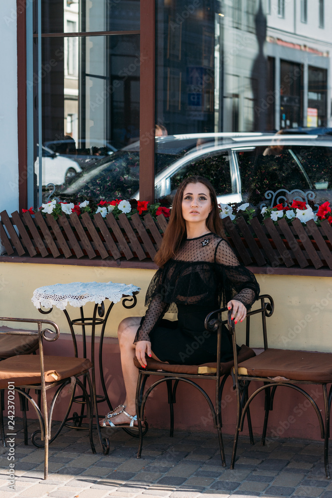 portrait of a beautiful, young, attractive girl who sits on the street in a cafe. waiting for breakfast, summer, date. dream